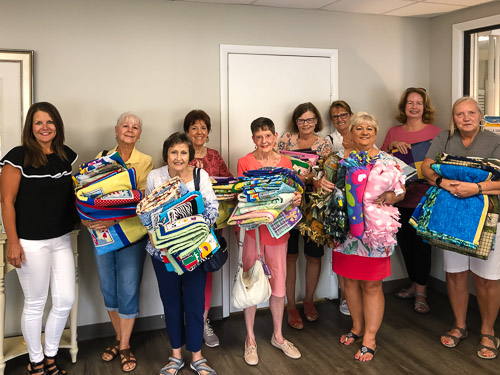 Group of women holding quilt donations at Anchorage Children's Home.