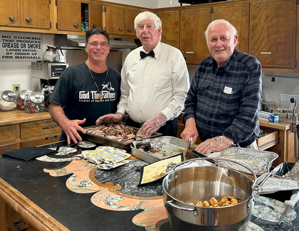 Three men prepare a large meal.