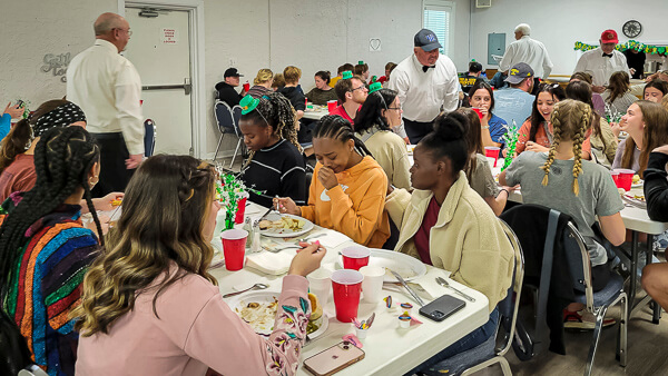 Large group of young people eat dinner.