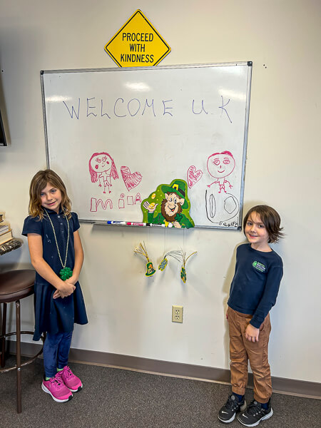 Two children show their welcome on a whiteboard for Christian Student Fellowship college students from Kentucky.