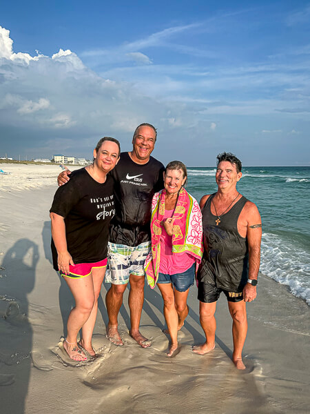 Four wet people at the beach after being baptized