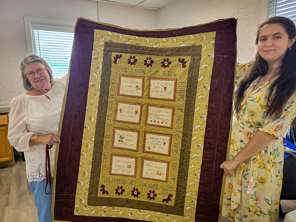 Graduate and Grandmother hold up a quilt given as a gift
