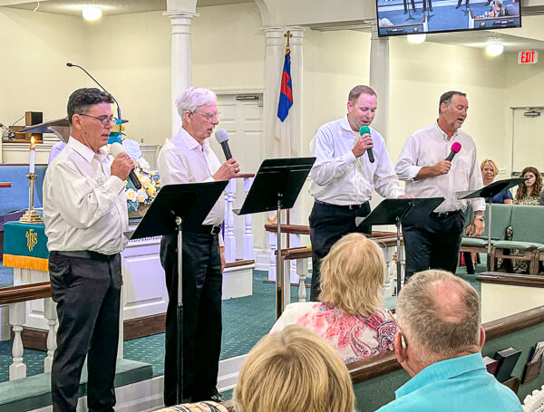A quartet of four men sing together during worship.