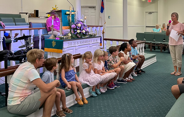 Several children listening to adult teaching a Children's Moment during worship service