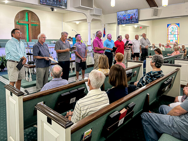 Pastor honors ten men standing in front of the congregation for completing the Resolution for Men course.