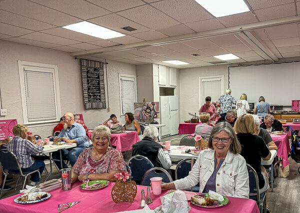 People enjoy a meal with pink decorations.
