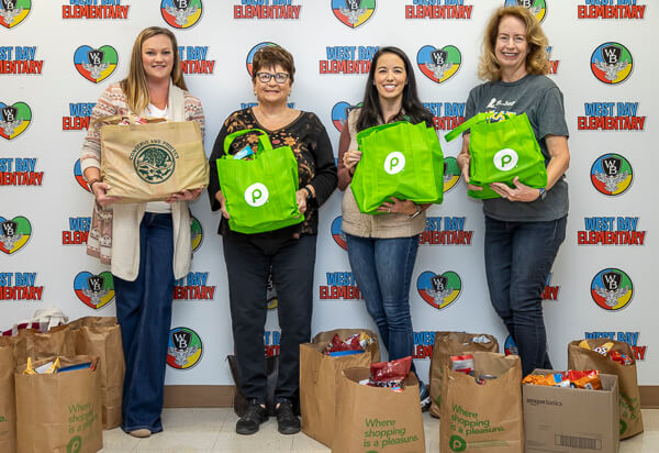 Women at West Bay Elementary hold groceries donated for Thanksgiving.