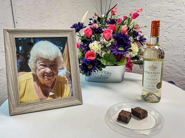 Photograph, flowers, brownies, and wine on table at Memorial Service.