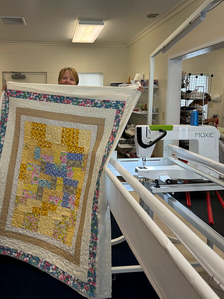 Woman holds up hand made quilt