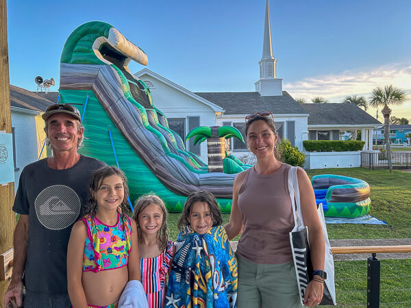 Adults and children stand in front of water slide