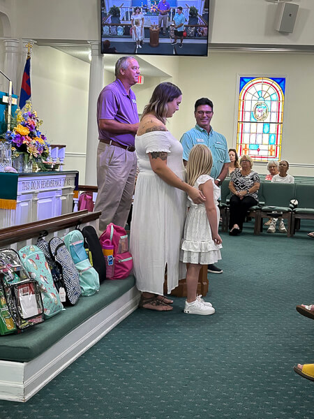 Young woman and child are about to be baptized at worship service.