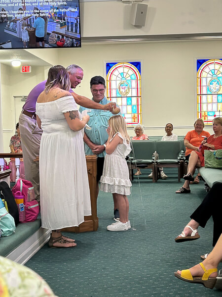 Young girl gets baptized in worship service as her mother looks on