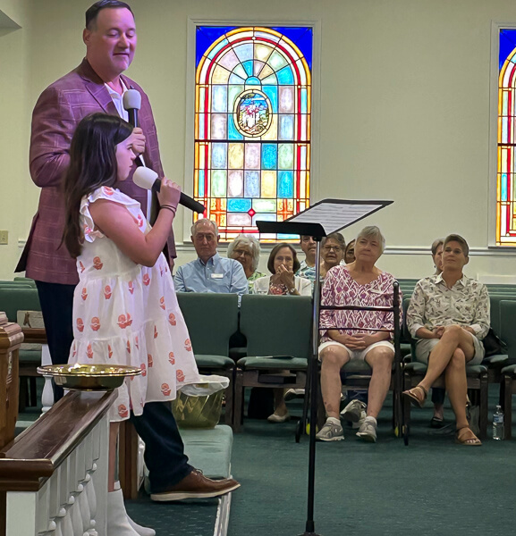 Man and young girl sing during church service