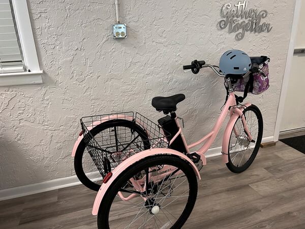 Pink 3 wheeled biked with basket and helmet