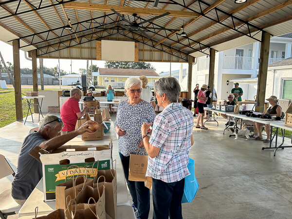 Two women buy an onion at Farmer's Market