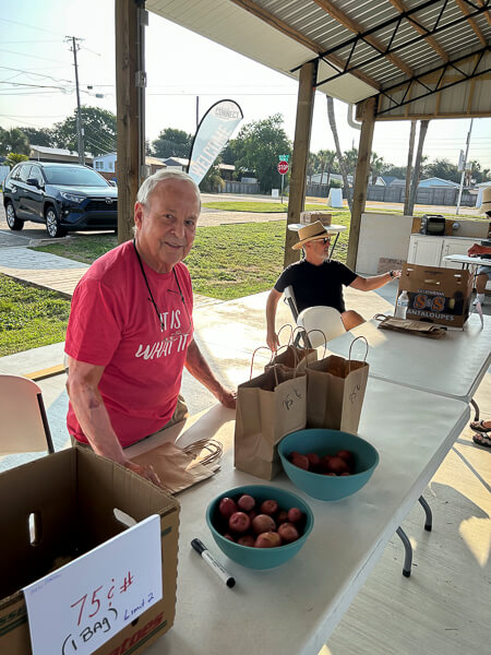 Smiling man works a Farmer's Market Table