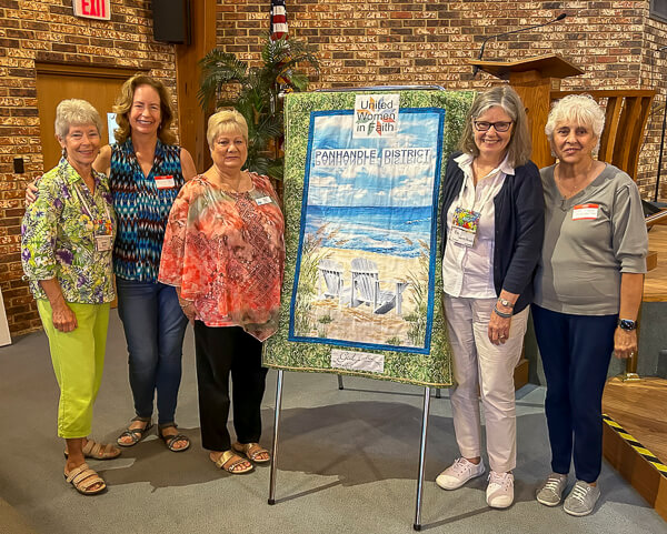 Five women stand beside banner for new UWF district.