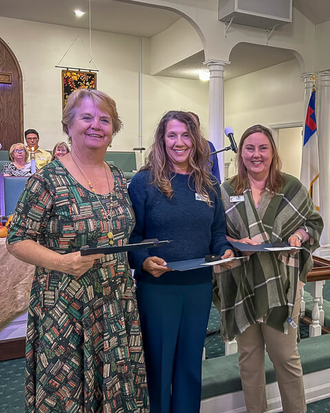 Three women receive pins from UWF during morning worship service.