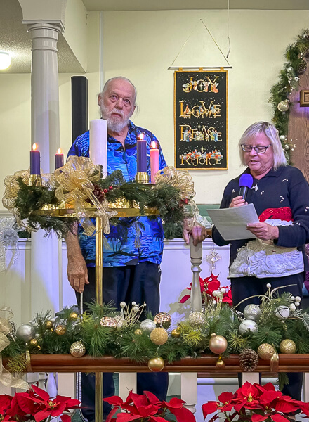 Man and woman stand behind the Advent Wreath