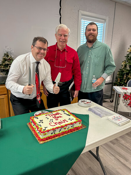 Three male choir members show interest in a choir cake