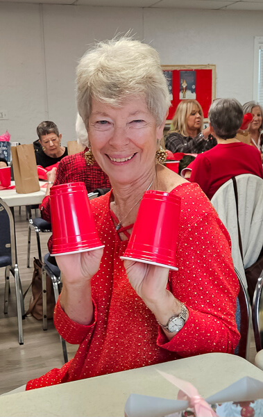 Pretty lady gives a big smile with red cups on her hands