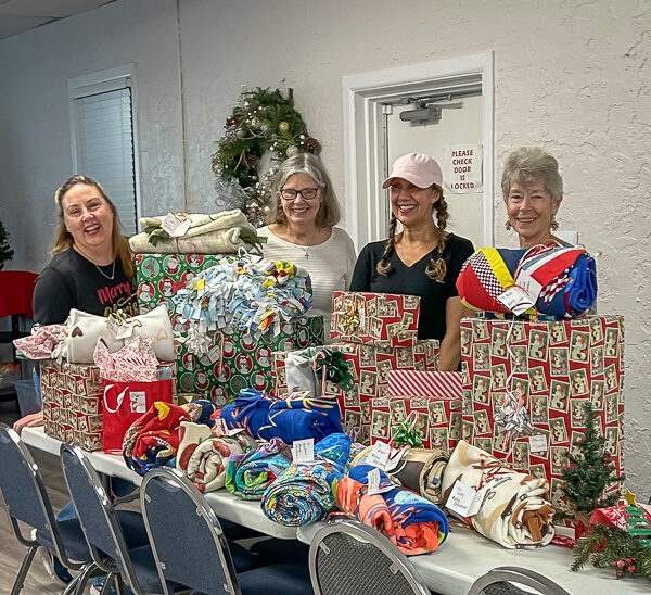 Women stand behind gift bags and quilts for Ark children.