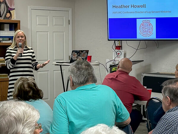 Woman speaks to people in Fellowship Hall