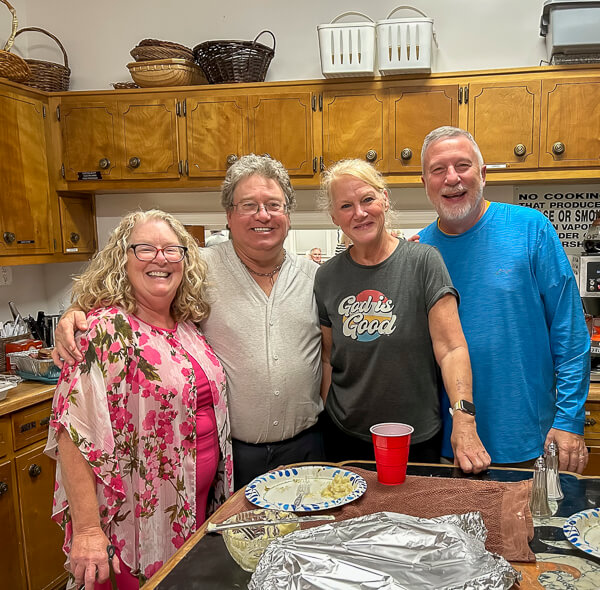 Four people stand together in kitchen