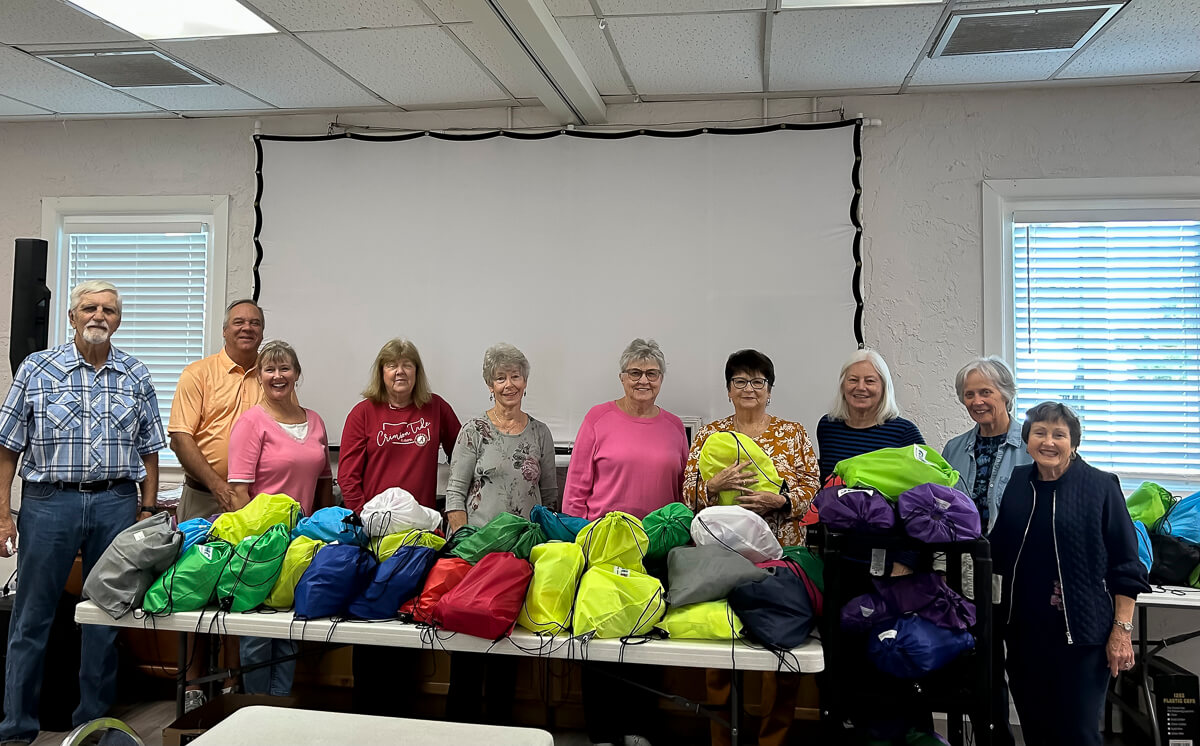 Group of people stand behind table full of blessing bags for people without homes