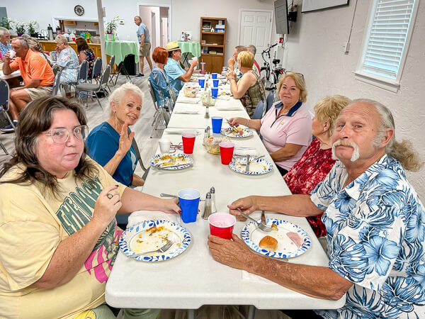 Groups of people eat together in Fellowship Hall.