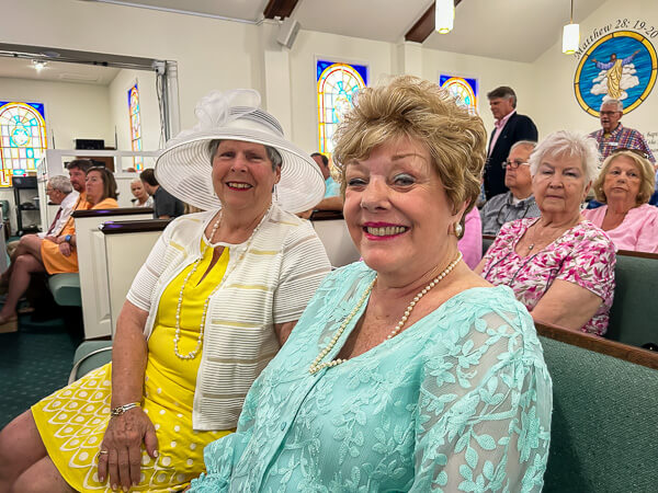 Two women in church look beautiful in Easter dresses.