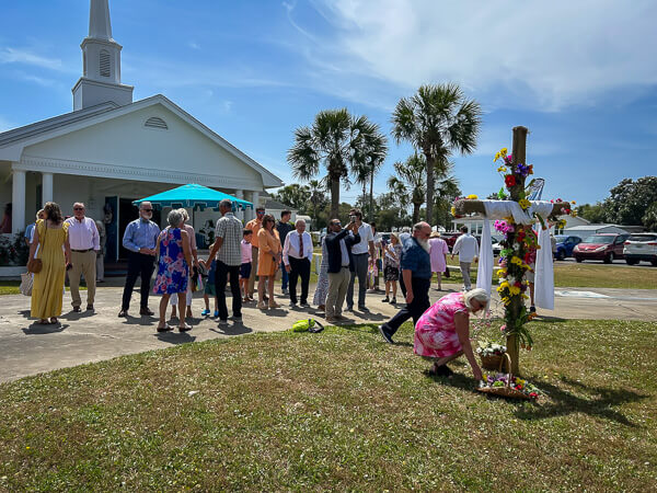 People add flowers to the flower cross in front of the church on Easter.