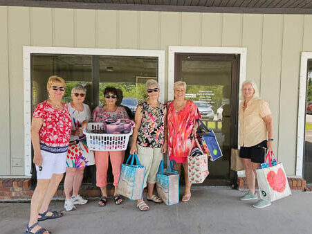 Ladies gather with quilts outside of a building
