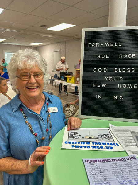 Woman gives a nice smile beside a sign of well wishes