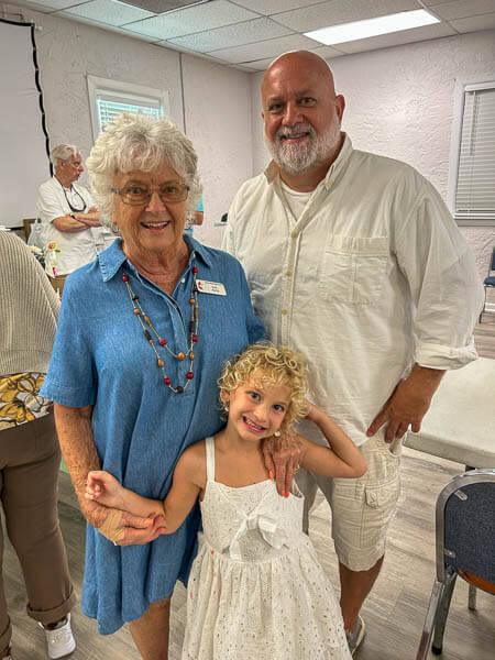 Woman, son, and granddaughter pose in Gulfview fellowship hall.