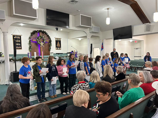 Pastor welcomes long line of children in front of the sanctuary