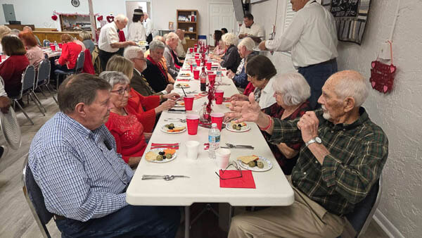 Tables of people eat in the fellowship hall