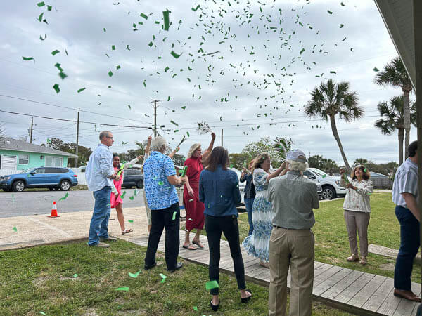 Choir members process in waving palm branches with confetti falling on them.