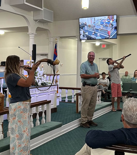 Man and woman blow horns during worship service