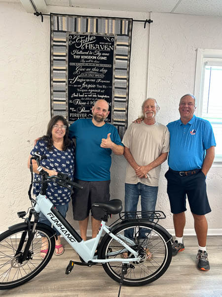 Three men and a woman stand behind a new e-bike.