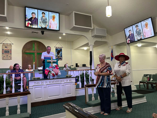 Three women are recognized for service during worship.